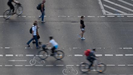 Fußgänger und Radfahrer bewegen sich auf einem Fußgänger- und Fahrradübergang auf einer Straße. 