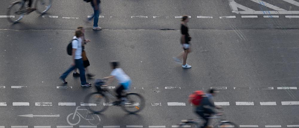 Fußgänger und Radfahrer bewegen sich auf einem Fußgänger- und Fahrradübergang auf einer Straße.