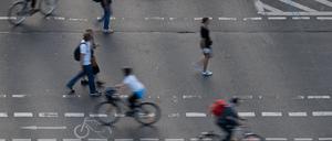 Fußgänger und Radfahrer bewegen sich auf einem Fußgänger- und Fahrradübergang auf einer Straße. 