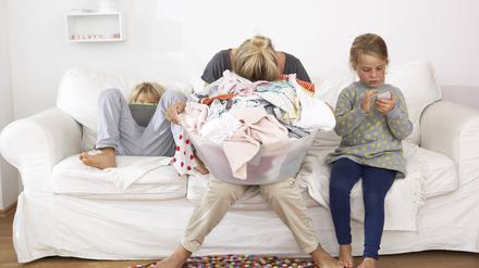 Eine erschöpfte Mutter neben ihren Kindern.