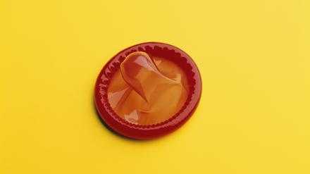 A red, rubber condom on a yellow background.