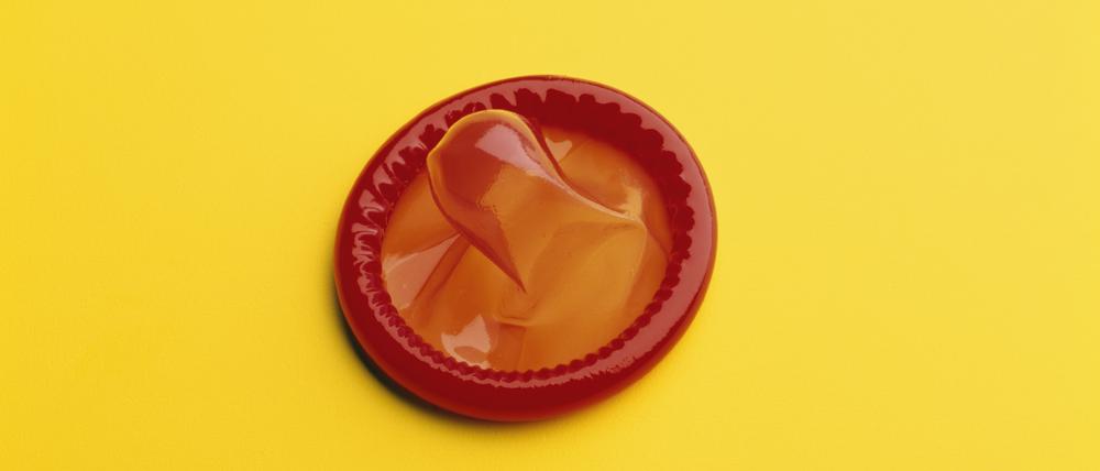 A red, rubber condom on a yellow background.
