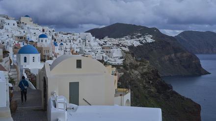  Ein Tourist nähert sich einer orthodoxen Kirche mit blauer Kuppel in Oia auf der erdbebengeschädigten Insel Santorini. 