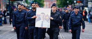 Polizisten tragen bei einem Trauermarsch für den bei einer Messerattacke am 31. Mai 2024 tödlich verletzten Polizisten Rouven L. dessen Bild. 