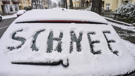 „Schnee“ steht auf einem verschneiten Auto in Berlin-Friedenau. (Symbolbild)