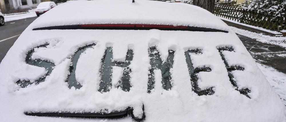 „Schnee“ steht auf einem verschneiten Auto in Berlin-Friedenau. (Symbolbild)