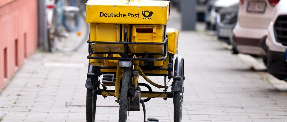 Ein Fahrrad eines Briefträgers steht auf einem Gehweg - auch dieser Briefträger möchte vermutlich gern deutlich besser bezahlt werden.
