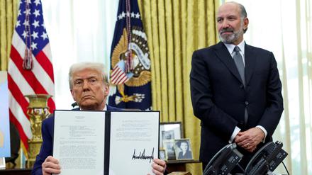 US-Präsident Donald Trump hält eine Durchführungsverordnung über die Erhöhung von Zöllen, flankiert von US-Handelsminister Howard Lutnick, im Oval Office des Weißen Hauses in Washington, D.C., USA, in der Hand.