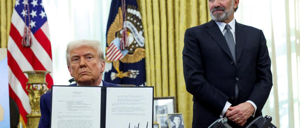 US-Präsident Donald Trump hält eine Durchführungsverordnung über die Erhöhung von Zöllen, flankiert von US-Handelsminister Howard Lutnick, im Oval Office des Weißen Hauses in Washington, D.C., USA, in der Hand.