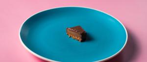 Uneaten slice sweet dessert chocolate bar on colored plate on pink background.