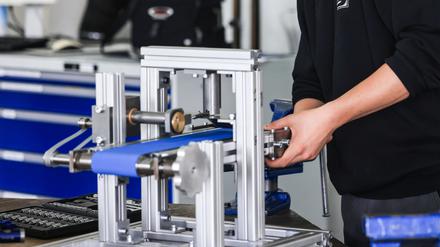 Ein Auszubildender zum Mechatroniker arbeitet an einer Ausbildungswerkstatt an der Standbohrmaschine. 