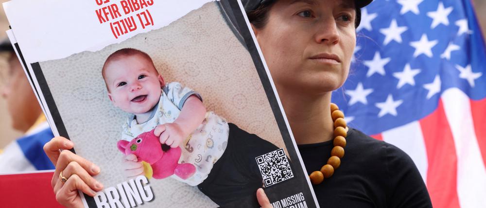 A woman holds a sign with a picture of Kfir Bibas, who was kidnapped during the deadly October 7 2023 attack by Hamas, as supporters and relatives of hostages held in Gaza gather in front of the White House prior to Israeli Prime Minister Benjamin Netanyahu's meeting with U.S. President Donald Trump, in Washington, U.S., February 4, 2025. REUTERS/Kevin Lamarque