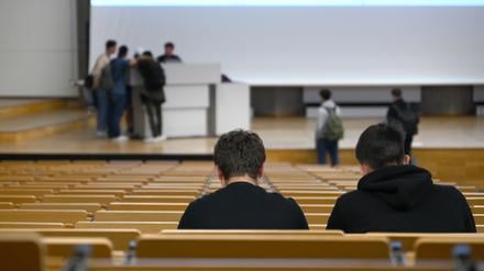 Zwei Studenten sitzen vor einer Vorlesung in einem Hörsaal in einer Universität. 