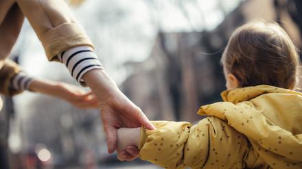 Ein Kleinkind läuft an der Hand der Mutter.