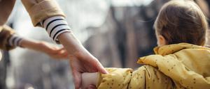 Ein Kleinkind läuft an der Hand der Mutter.