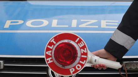 Eine Anhaltekelle vor einem Dienstauto der Thüringer Polizei. 