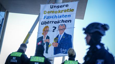 Polizeibeamte stehen am Paul-Löbe-Haus an einem Protestbanner, das gemalte Bilder von Alice Weidel, Kanzlerkandidatin der AfD, und Unions-Kanzlerkandidat Friedrich Merz zeigen soll. 