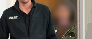 Eine angeklagte Frau betritt einen Verhandlungssaal in einem Landgericht. 