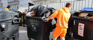  Mitarbeiter der BSR bewegt eine volle Restmülltonne. 