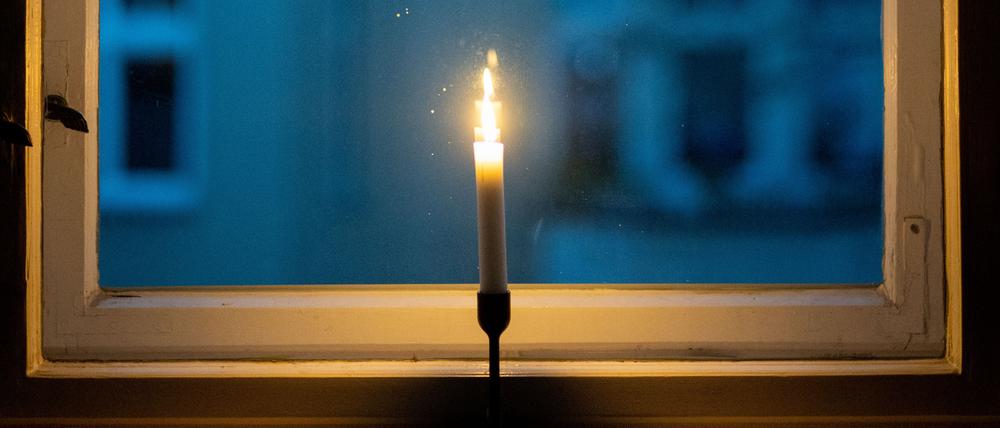 Eine Kerze brennt in einem Fenster