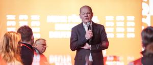 Bundeskanzler Olaf Scholz (M, SPD) spiegelt sich beim Wahlkampfabschluss in seinem Wahlkreis in einer Tischscheibe.