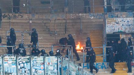 Nach dem Spiel räumen Polizisten den Gästeblock, wo es teilweise brennt.