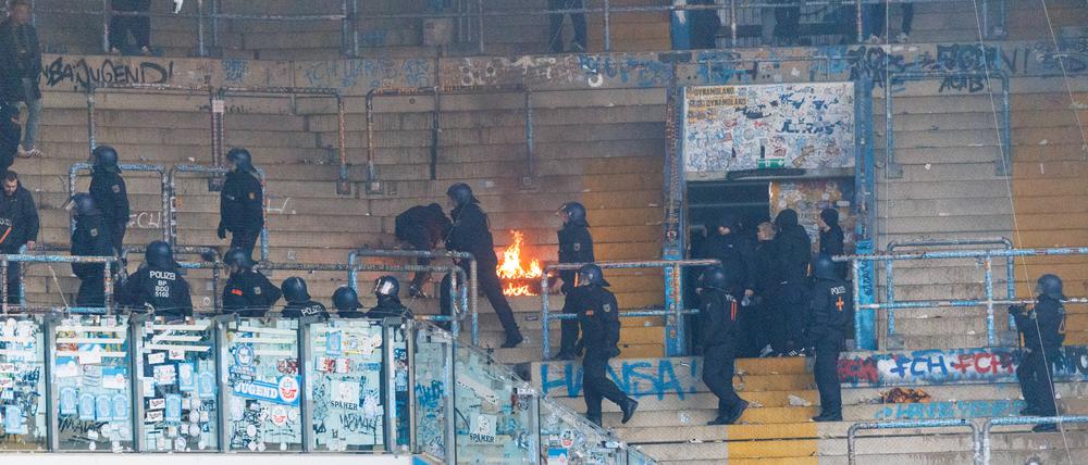 Nach dem Spiel räumen Polizisten den Gästeblock, wo es teilweise brennt.