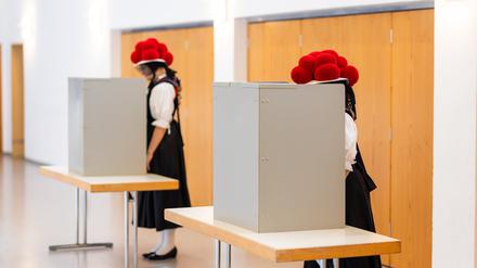 Gutach: Zwei junge Frauen stehen in traditioneller Schwarzwälder Tracht mit Bollenhut in der Wahlkabine. 