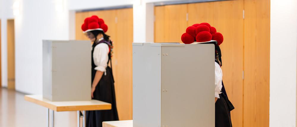 Gutach: Zwei junge Frauen stehen in traditioneller Schwarzwälder Tracht mit Bollenhut in der Wahlkabine. 