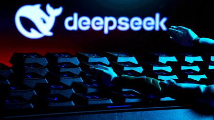 Deepseek-Logo, darunter Hände auf einer Tastatur