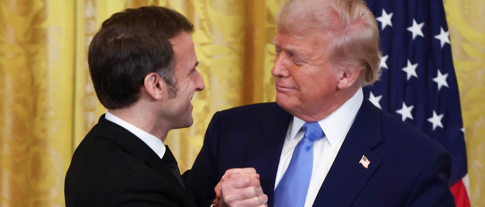 U.S. President Donald Trump and French President Emmanuel Macron look at each other on the day of a press conference, at the White House in Washington, D.C., U.S., February 24, 2025. REUTERS/Evelyn Hockstein