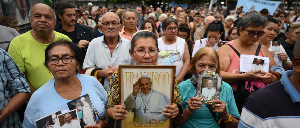Menschen halten Porträts von Papst Franziskus, während sie an einer Messe für seine Heilung auf dem Platz der Verfassung in Buenos Aires teilnehmen.