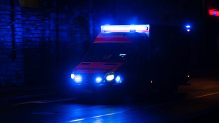 Ein Krankenwagen fährt nachts mit Blaulicht durch eine Straße. (Symbolbild)