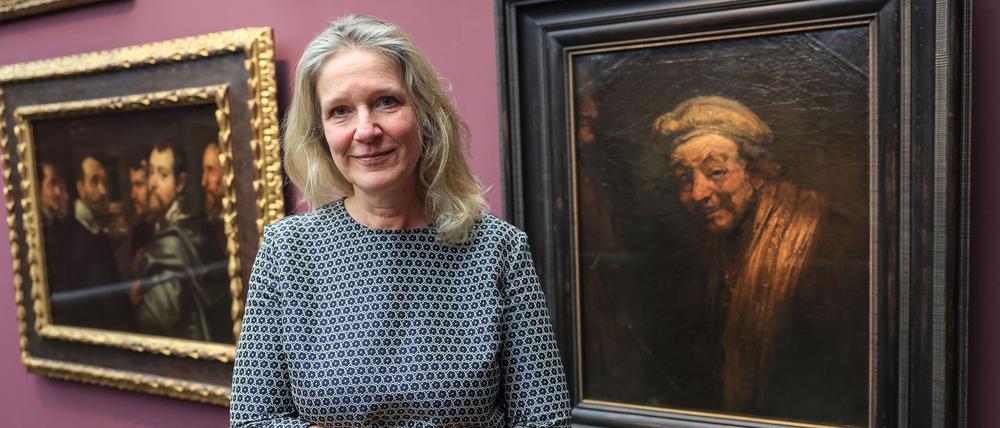 Anja Sevcik steht zwischen einem Selbstbildnis von Peter Paul Rubens unter Freunden (links) und einem Selbstbildnis von Rembrandt (rechts).