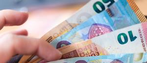 Eine Frau hält ein Portemonnaie in der Hand, in dem Geldscheine stecken. 