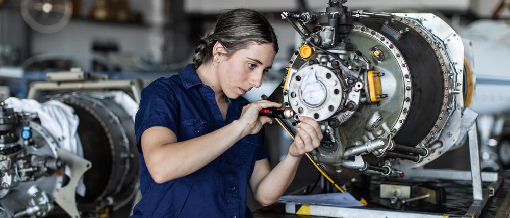 Eine Ingenieurin bei ihrer Arbeit mit Flugzeugtechnik (Symbolbild)