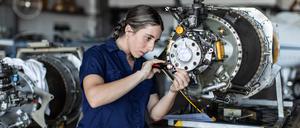 Eine Ingenieurin bei ihrer Arbeit mit Flugzeugtechnik (Symbolbild)