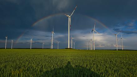 Ein Regenbogen ist vor dunklen Wolken am Abend über der Landschaft mit einem Windenergiepark im Osten von Brandenburg zu sehen. 