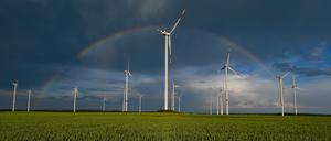 Ein Regenbogen ist vor dunklen Wolken am Abend über der Landschaft mit einem Windenergiepark im Osten von Brandenburg zu sehen. 