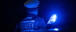 Ein Polizist steht neben einem Polizeifahrzeug. (Symbolbild)