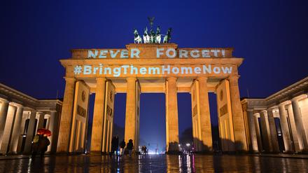 Die Schriftzüge „Never forget“ (Niemals vergessen) und „#BringThemHomeNow“ (Bringt sie nachhause) werden auf das orange angestrahlte Brandenburger Tor projiziert.