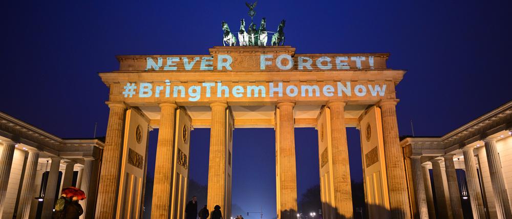 Die Schriftzüge „Never forget“ (Niemals vergessen) und „#BringThemHomeNow“ (Bringt sie nachhause) werden auf das orange angestrahlte Brandenburger Tor projiziert.