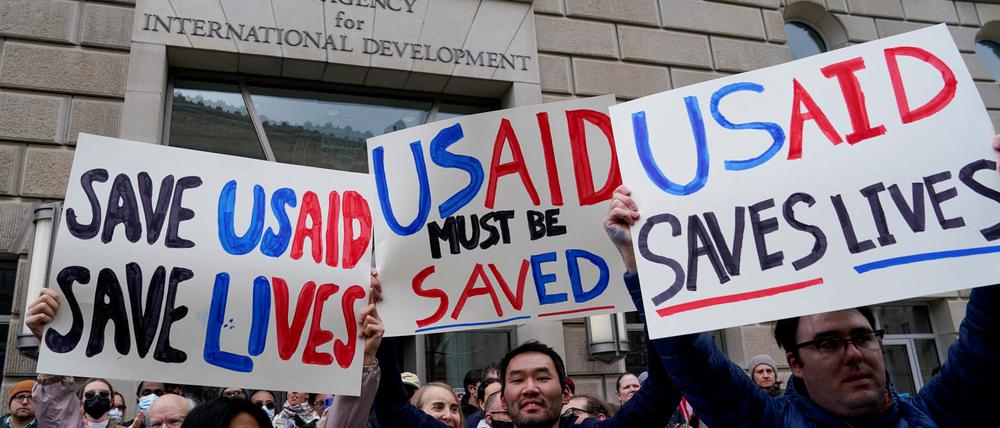 Menschen halten Plakate, während das USAID-Gebäude für Mitarbeiter geschlossen bleibt (Symbolbild).