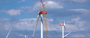 Ein Kran hebt auf der Baustelle eines neuen Windparks ein Rotorblatt für die Montage an das Generatorhaus (Symbolbild).