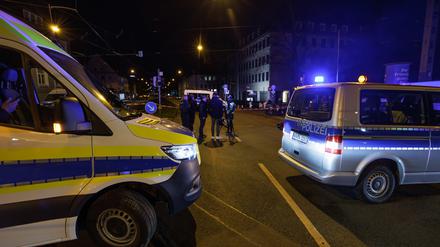 Einsatzkräfte der Polizei stehen neben Einsatzfahrzeugen am Tatort in der Bielefelder Innenstadt.