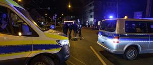 Einsatzkräfte der Polizei stehen neben Einsatzfahrzeugen am Tatort in der Bielefelder Innenstadt.