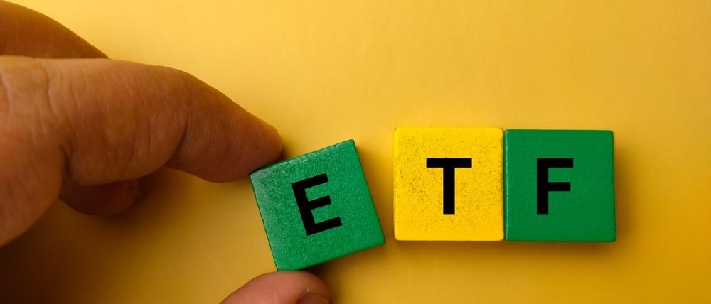 Hand hält Würfel mit der Aufschrift „E“, daneben liegen Würfel mit den Buchstaben „T“ und „F“.