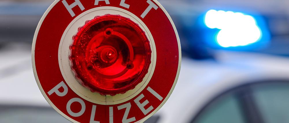 Ein Polizist hält eine Polizeikelle für eine Kontrolle.