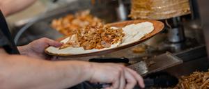 Ein Mitarbeiter einer Dönerbude legt Fleisch auf einen Döner.