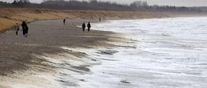 ARCHIV - 05.01.2023, Mecklenburg-Vorpommern, Wustrow: Spaziergänger sind am Ostseestrand unterwegs, während der stürmische Wind weißen Schaum an das Ufer treibt. Schädliche PFAS-Chemikalien, auch Ewigkeitschemikalien genannt, finden sich einer Greenpeace-Studie zufolge in angespültem Meeresschaum an Stränden an der deutschen Nord- und Ostseeküste. (zu dpa: «Landesregierung für weitgehendes Verbot von PFAS-Chemikalien») Foto: Bernd Wüstneck/dpa +++ dpa-Bildfunk +++